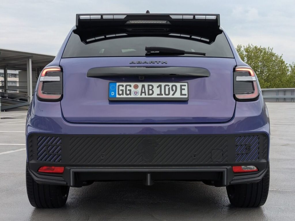 Heckansicht: Aerodynamische Anbauteile in der sportlichen Top-Version mit großem Dachspoiler und Heckdiffusor beim Abarth 600e.