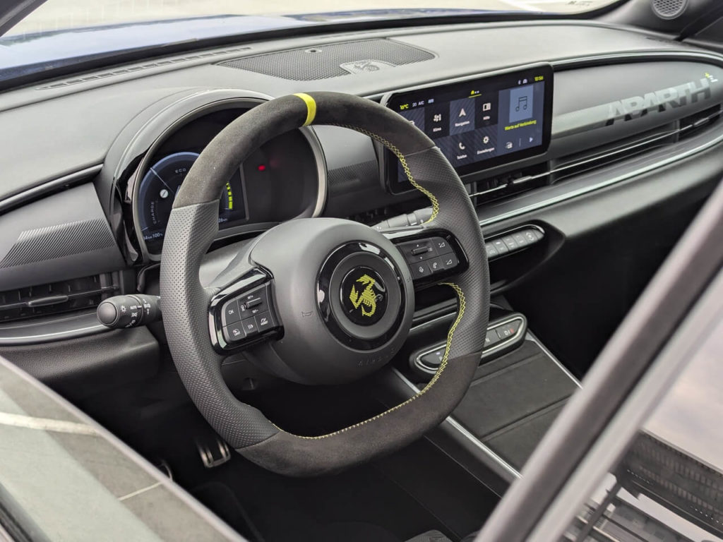 Alcantara Sportlenkrad im Abarth 600e Scorpionissima mit 12-Uhr-Markierung und gelb abgesetzten Ziernähten.