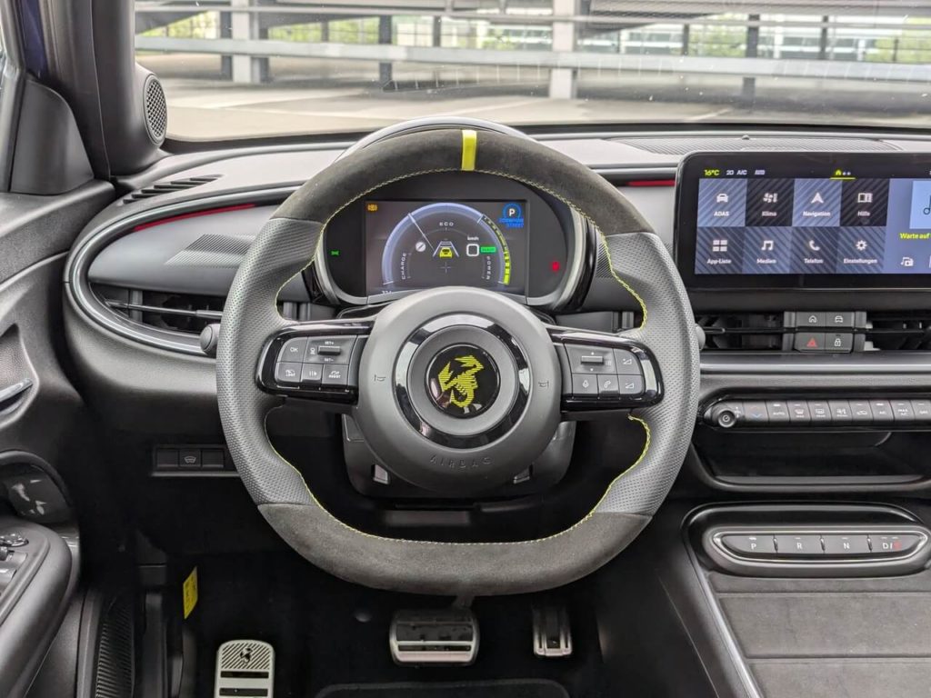 Fahrerperspektive: Alcantara-Sportlenkrad mit gelber 12-Uhr-Markierung und gelben Nähten. 7 Zoll großer Digitaltacho im Abarth-Design.