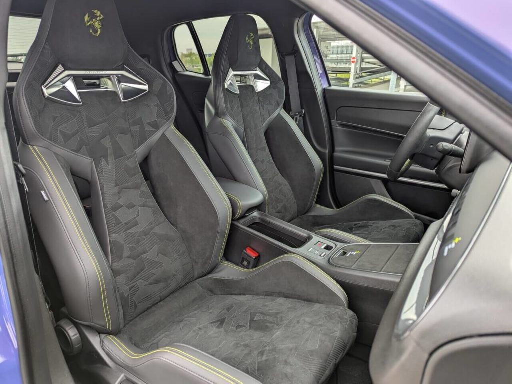 Alcantara-Sportschalensitze von SABELT im Abarth 600e Scorpionissima: offene Rückenlehne und gelbe Highlights (Skorpion in der Kopfstütze und Ziernähte).