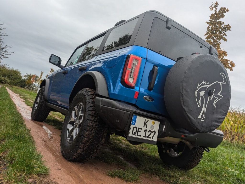 Ford Bronco mit Ersatzrad am Heck und originaler Schutzhülle mit Pferd-Print.