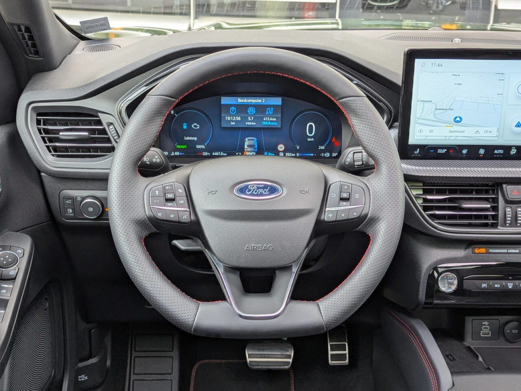 POV: Fahrerperspektive beim Ford Kuga ST-Line X: Digitaltacho und Sportlenkrad mit perforiertem Leder und roten Ziernähten