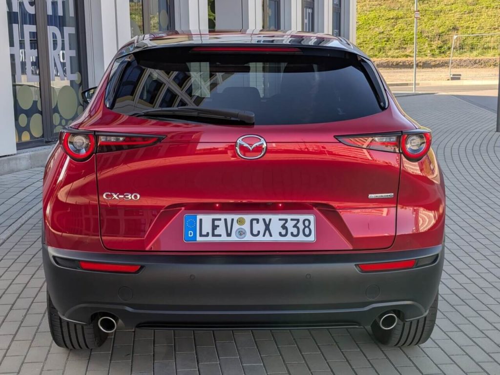 Heckansicht des Mazda CX30 in Soul Red Crystal mit doppelflutiger Auspuffanlage.