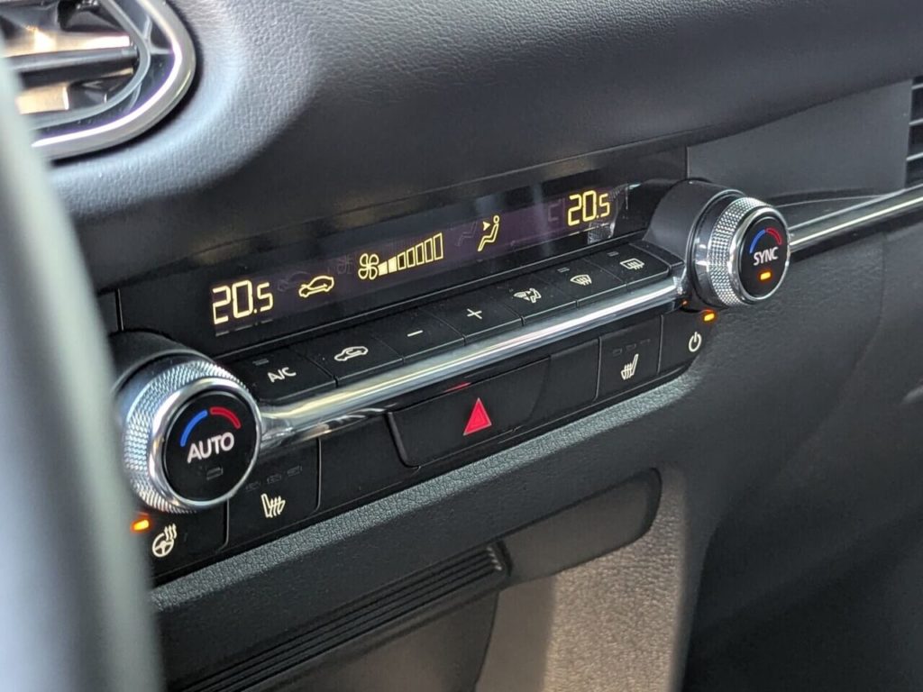 2-Zonen Klimaautomatik mit Drehreglern zur Temperaturregelung und physischen Tasten zur Steuerung von Lenkradheizung und Sitzheizung.