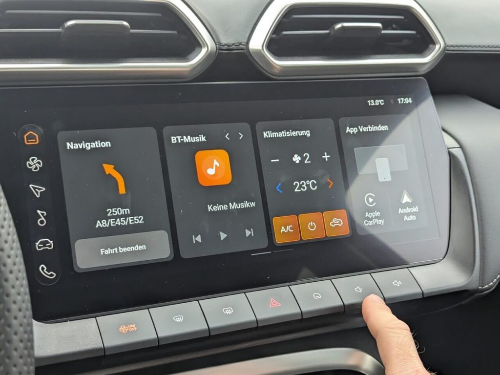 Infotainmentsystem im MG ZS Hybrid+ mit 12,3 Zoll Touchscreen und kabelgebundene Smartphone-Integration (Android Auto und Apple CarPlay). Direktwahltasten: Home-Button, Lautstärke.