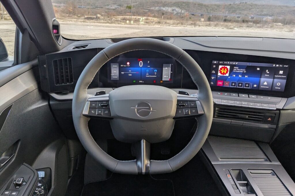 Fahrerperspektive beim Opel Astra L (Facelift): 10 Zoll Digital-Kombiinstrument, 3-Speichen-Lenkrad ohne Klavierlack mit Schaltpaddels für Rekuperation.