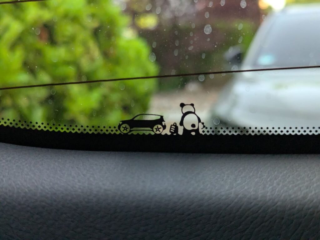 Panda-Easter-Egg an der Heckscheibe des Smart #5 mit Koffer neben dem Fahrzeug.