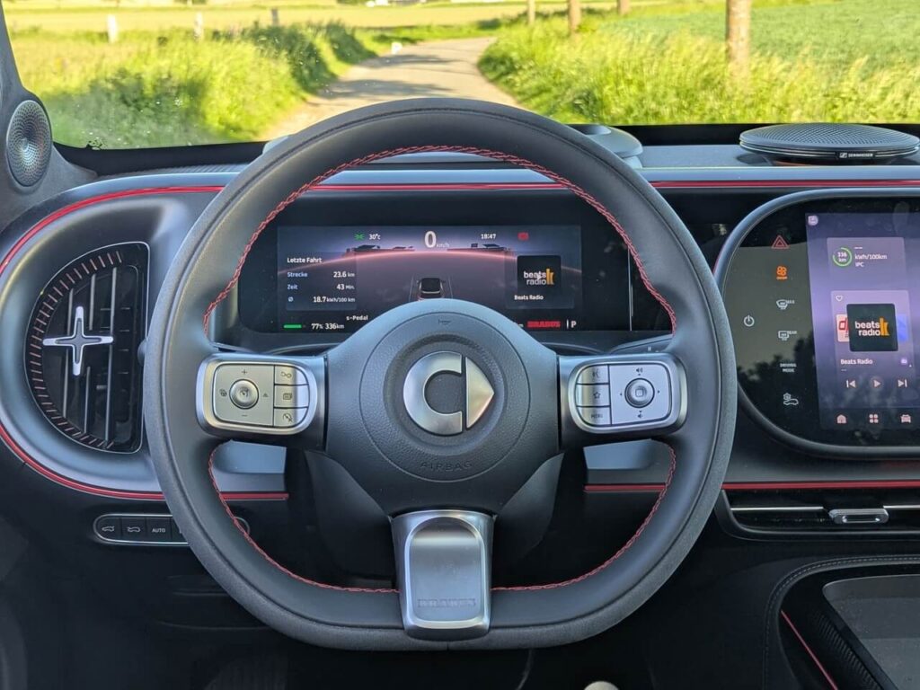 Fahrerperspektive im Smart #5 Brabus: Alcantara Sportlenkrad mit roten Ziernähten und 10,25 Zoll großer HD-Instrumenteneinheit.