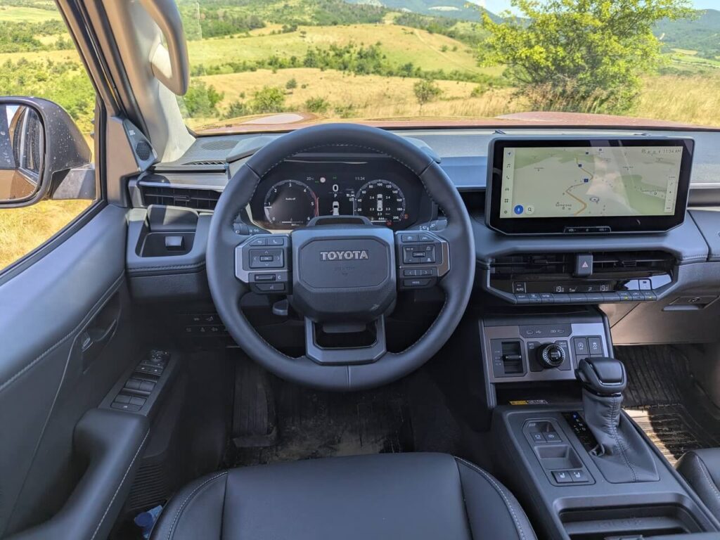 Fahrerperspektive im Toyota Hilux (9. Modellgeneration) mit modernen Interieur und neuem Lenkrad.