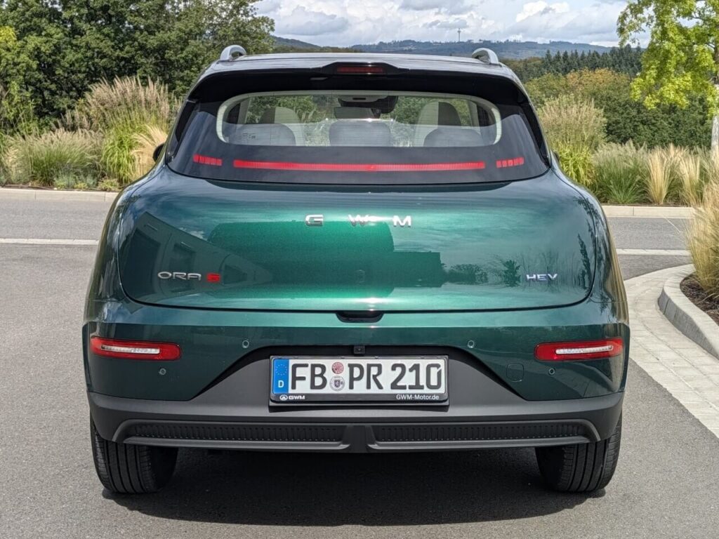 Heckansicht beim GWM ORA 5 HEV (Hybrid-Version) in "Forest Green Metallic". Die Rückleuchten sind in die Heckscheibe integriert.