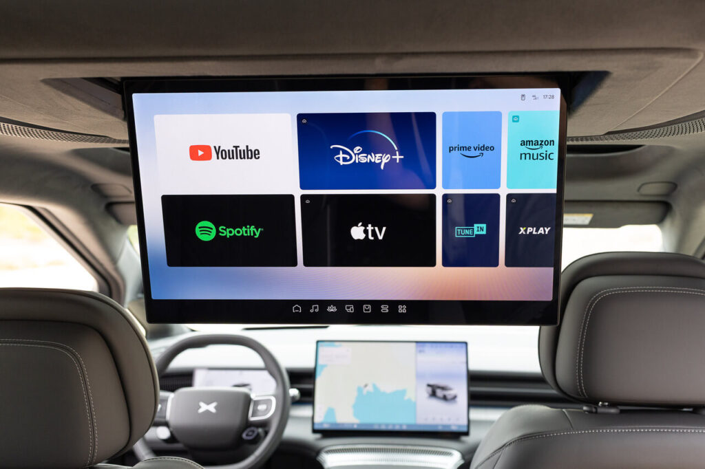 Read-Seat-Entertainment mit riesigem runterklappbaren Bildschirm im Elektro-Van Xpeng X9 mit verschiedenen Streaming-Diensten.