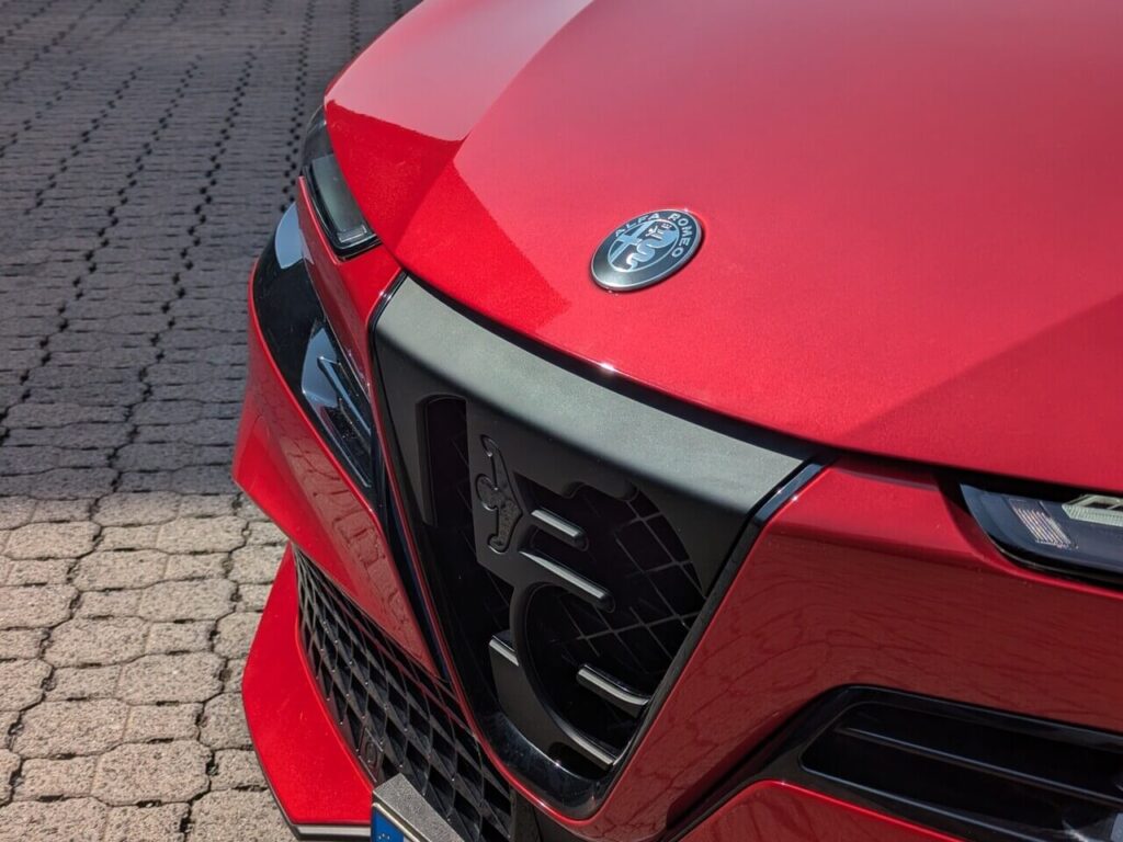 Scudetto Progresso: Kühlergrill mit Alfa-Romeo-Markenlogo an der sportlichen Front beim Junior Veloce in der Lackierung "Rosso Brera" (3-Schicht-Metallic-Lackierung).